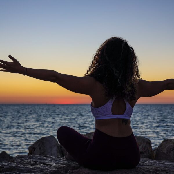 woman wearing sports bra sitting in front of the ocean