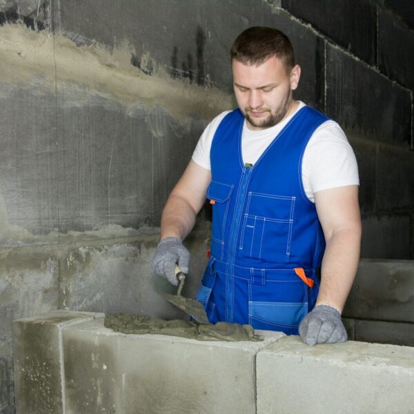 a man in blue overalls working on cement