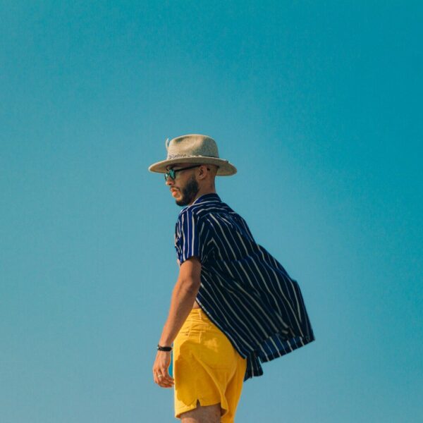 Man in stylish summer outfit posing under blue sky.